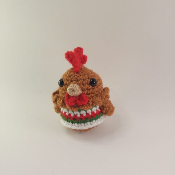 A crochet Christmas chicken with a white background