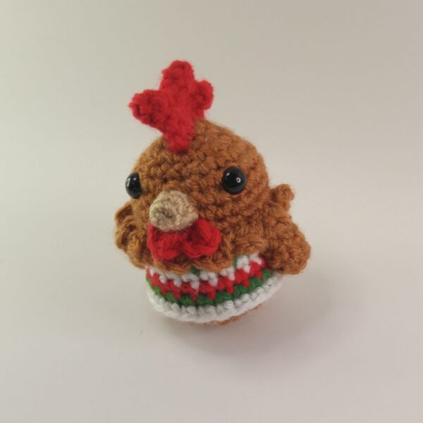 A crochet Christmas chicken with a white background