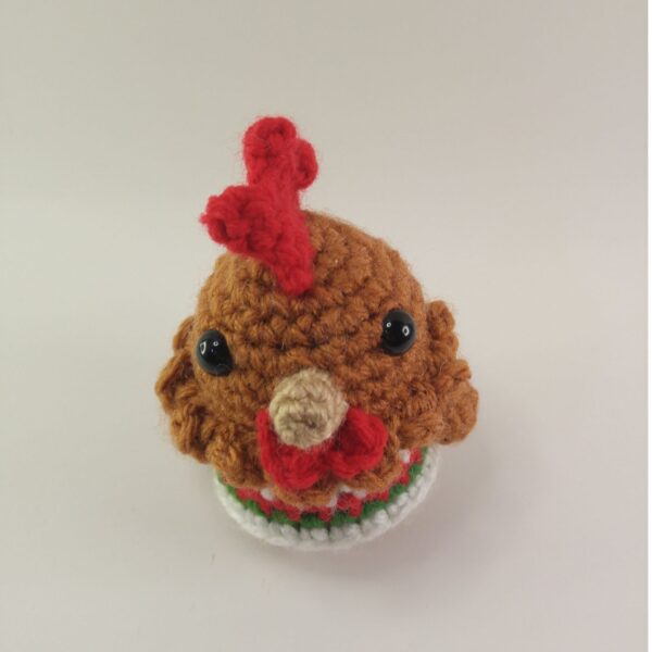 A crochet Christmas chicken with a white background