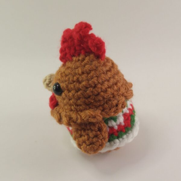 A crochet Christmas chicken with a white background