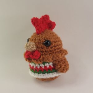 A crochet Christmas chicken with a white background