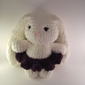 A white crochet jumbo bunny with a purple skirt on