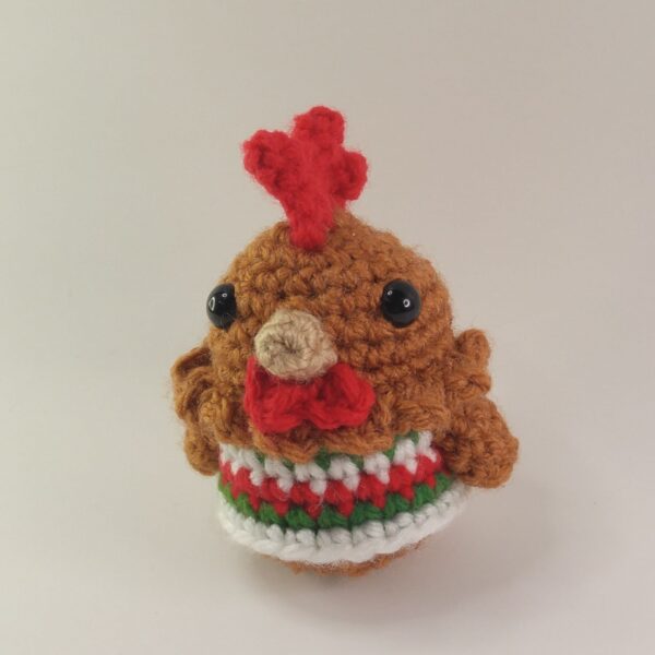 A crochet Christmas chicken with a white background